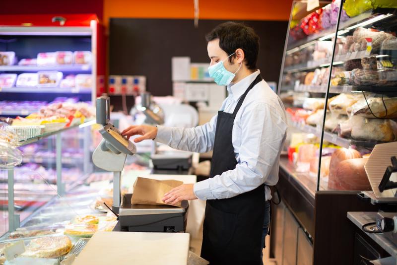 Shopkeeper with mask in Italian deli 