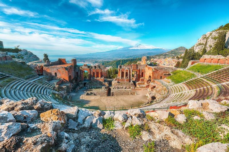 Ruins of ancient Greek theater in Taormina and Etna volcano in the background