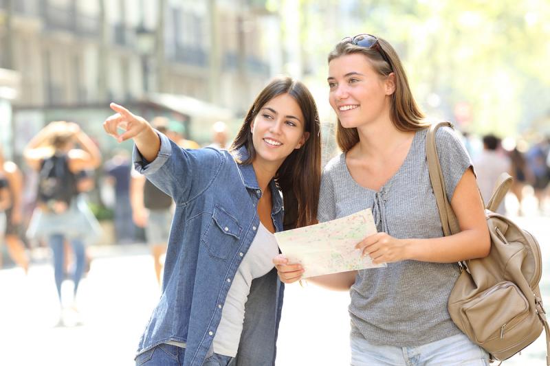 Happy girl helping to a tourist who asks direction in the street